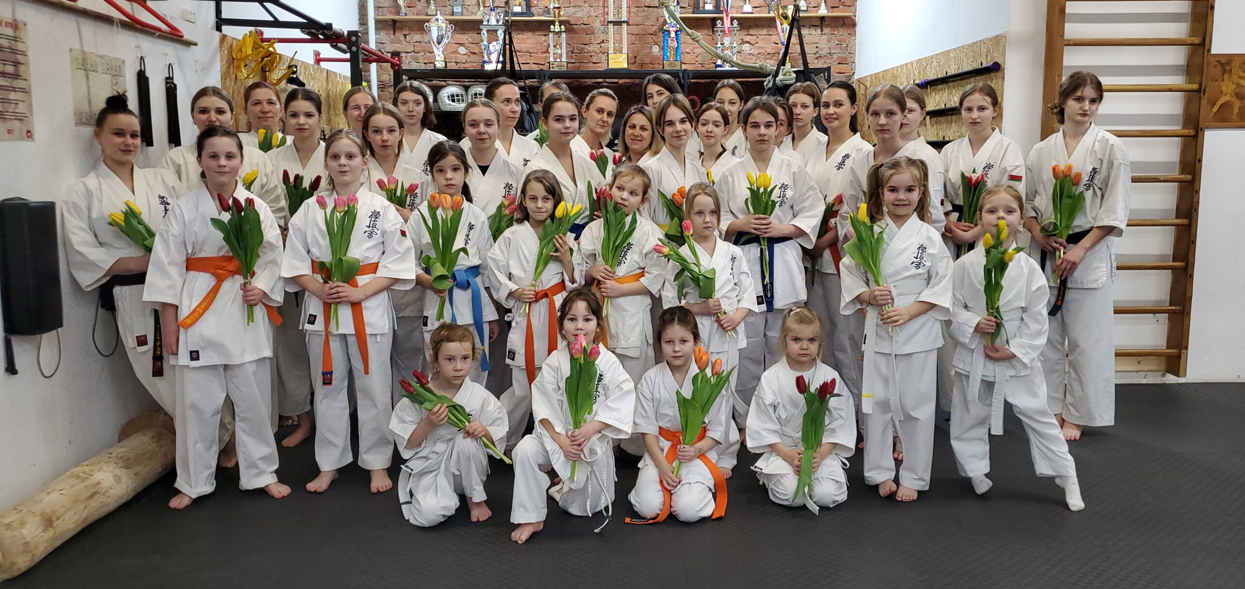 Девочки, девушки и женщины в кимоно держат тюльпаны, которые им подарили коллеги из клуба Школа Мужества в честь восьмого марта.